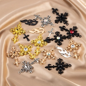 Détail de pendentifs croix en alliage avec strass colorés sur tissu satin champagne