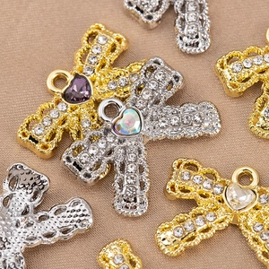 Detailed view of cross heart charms with crystals on champagne velvet fabric