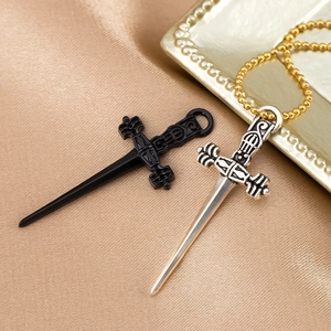 Détail de pendentifs dague noir mat et argent antique sur tissu satiné