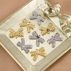 Macro detail of rhinestone bow heart pendants in gold and silver finish for DIY jewelry