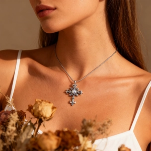 Détail d'un collier croix vintage avec gravures ajourées et pierre précieuse centrale