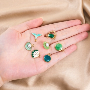 Gedetailleerde weergave van emaille hangers met zeethema in groen voor DIY sieraden