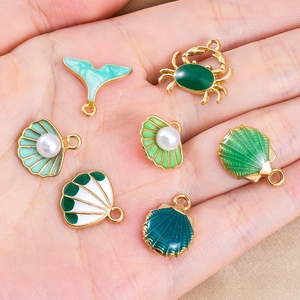 Macro-opname van goudkleurige zeehangers met groen emaille en parels voor DIY sieraden