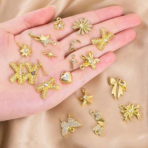 Macro shot of gold alloy butterfly and heart charms with rhinestones held in hand