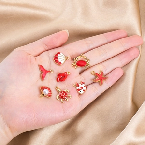Detalle de dijes marinos rojos y blancos sostenidos en la mano para el tamaño