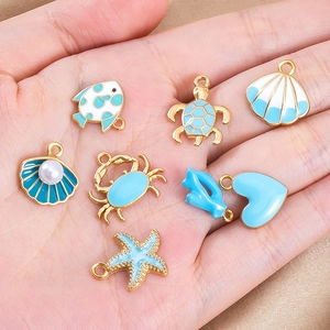 Blue enamel ocean charms set held in hand featuring turtle shell and starfish designs