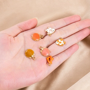 Detailed close-up of colorful enamel sea creature charms held in palm for DIY jewelry