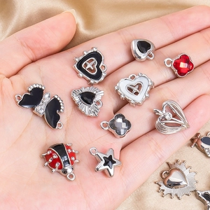 Detailed macro shot of DIY alloy charms with hearts, butterflies and rhinestones in hand