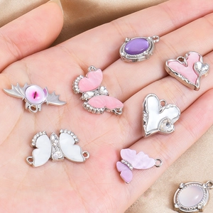Details von Herz- und Schmetterlingsanhängern für DIY-Schmuck in der Hand