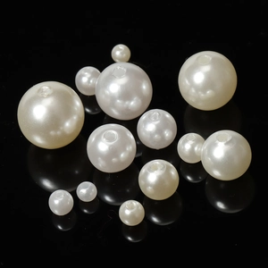 Macro shot of polished white ABS faux pearl beads with pre-drilled holes on black surface
