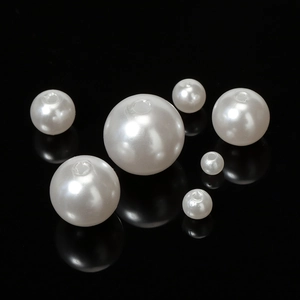 Macro shot of white polished ABS imitation round pearls with holes in various sizes
