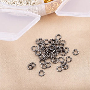 Détail d'anneaux ouverts noir fusil avec accessoires de bijoux DIY dans une boîte de rangement
