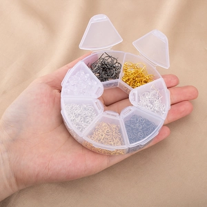 Main tenant une boîte ronde avec des crochets de boucles d'oreilles et anneaux DIY