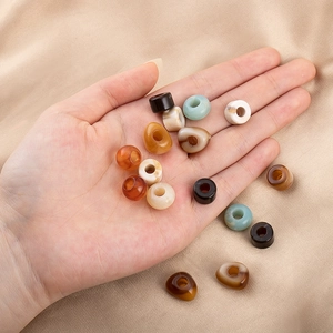 Makroaufnahme bunter marmorierter Acrylperlen für DIY-Schmuck auf goldener Seide