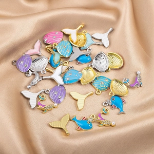 Detalle de colgantes de cola de ballena con esmalte de colores sobre fondo de satén