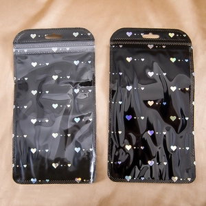 Detalle de bolsas negras holográficas de corazón con ventana transparente y orificio para colgar