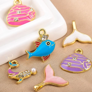 Detalle de dijes esmaltados de tema oceánico con colas de sirena para joyería artesanal