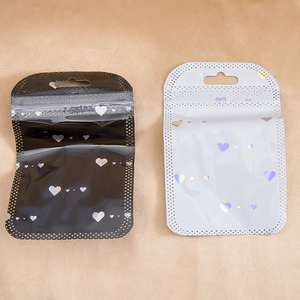 Detalle macro de patrones de corazones holográficos en bolsas de regalo negras y plateadas