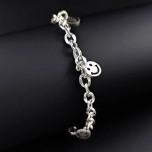 Detail eines silbernen Kettenglied-Armbands mit klassischem Smiley-Anhänger auf Ständer
