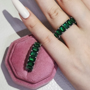 Close-up of emerald-cut green zircon eternity ring in silver band and velvet box