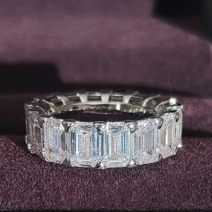 Macro view of emerald-cut zircon eternity ring in silver finish on purple velvet box
