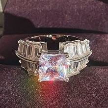 Macro shot of Princess cut diamond ring with tapered baguette side stones on velvet