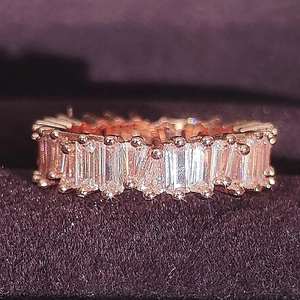 Makroaufnahme eines roségoldenen Eternity-Rings mit Zirkonia-Steinen auf lila Samtstoff