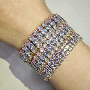 Vista macro de pulseras de tenis superpuestas en oro y plata con cristales brillantes