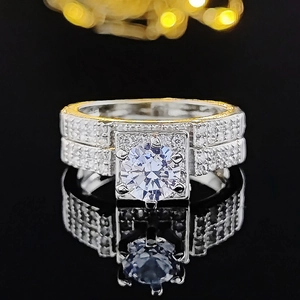 Elegant two-tone wedding ring set with round clear center stone on a black mirror surface