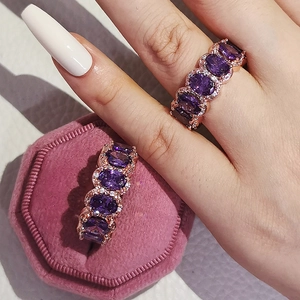 Detail of rose gold rings with oval purple stones in a pink velvet jewelry box