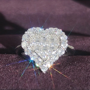 Sparkling heart shaped silver engagement ring with baguette cut stones on purple velvet