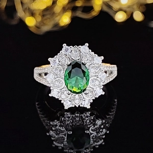 Luxuriöser blumenförmiger Smaragdring mit weißen Diamanten auf spiegelnder Oberfläche