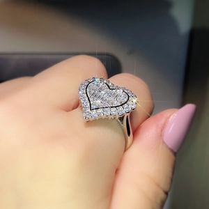 Sparkling silver heart engagement ring with cluster pavé stones shown on a female finger
