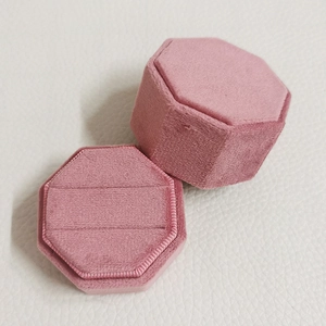 Roze fluwelen achthoekig sieradendoosje met twee ringgleuven op een leren basis