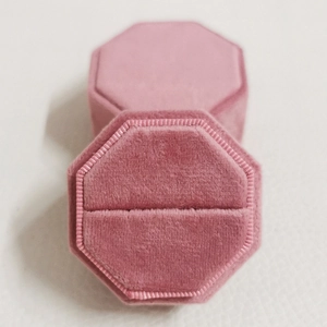 Elegante achthoekige roze fluwelen ringendoos met deksel op een zachte achtergrond