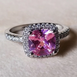 Macro detail of luxury pink cushion cut gemstone ring with halo diamond setting