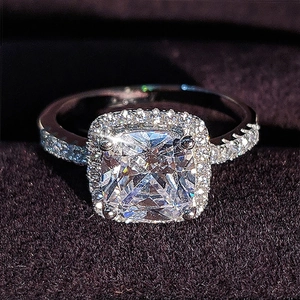 Macro shot of cushion cut halo engagement ring with pavé diamond band on purple velvet