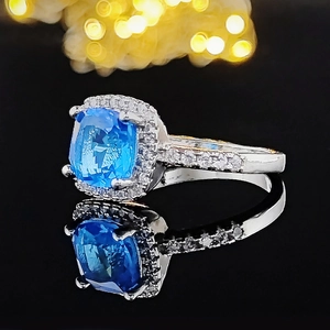 Macro shot of silver ring with large square blue gemstone and cubic zirconia accents
