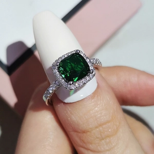 Macro shot of square cut green gemstone ring with halo diamonds on silver band