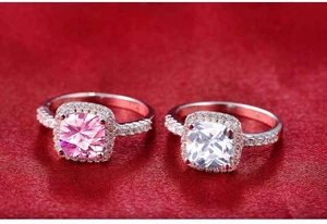 Macro detail of cushion cut pink and clear gemstone rings with pavé halo setting