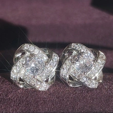 Gros plan d'une boucle d'oreille fleur en argent sertie de zircones sur velours violet