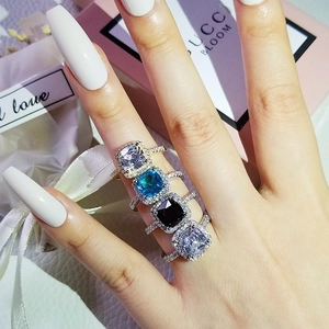 Detailed view of four colorful square halo rings with shimmering crystals on the band