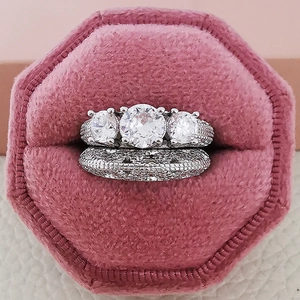 Juego de anillos de compromiso de tres piedras en un joyero de terciopelo rosa