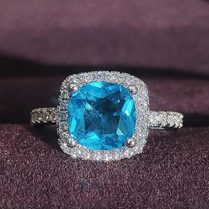 Luxurious cushion-cut blue gemstone ring with sparkling diamond halo on silver band