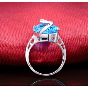 Dettaglio anello con gemma ovale blu, struttura in argento a Z e incisioni decorative