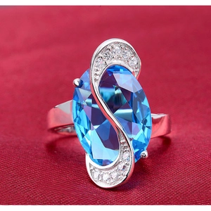Elegante anello da donna con gemma blu ovale e curva di diamanti a S su tessuto rosso