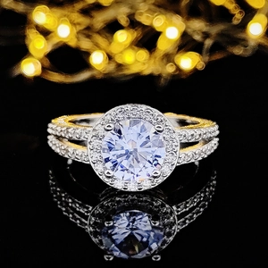 Luxe halo-ring met witte zirkoon en tweekleurig goud ontwerp op zwarte achtergrond