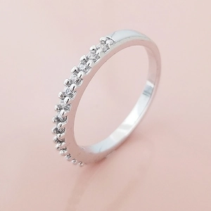 Bague demi-éternité argentée élégante avec zircons brillants sur fond rose doux