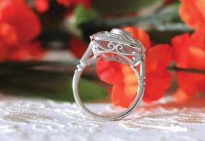 Detailed view of vintage silver ring with intricate hollow floral carvings and stone