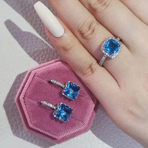 Elegant silver jewelry set featuring square blue halo ring and stud earrings in pink box